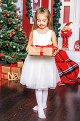 A little girl opens a gift box. Concept New Year, Merry Christmas, holiday, vacation, winter, childhood.