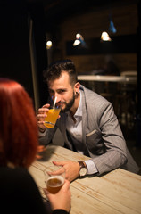 Man on a date in a pub, drinking beer, watching to camera