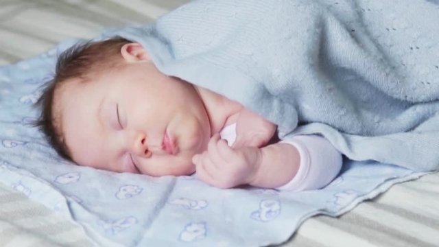 Newborn baby sleeping on a bed covered with a blue blanket