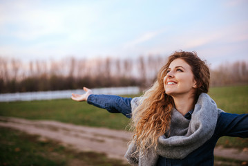 Side view portrait of delighted woman standing outdoors with her hands raised.