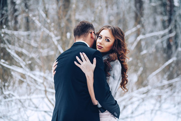 Happy young wedding couple in the winter forest