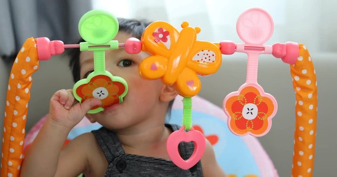 cute baby boy using hand playing toy put in mouth