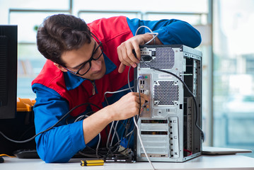 Computer repairman working on repairing computer in IT workshop