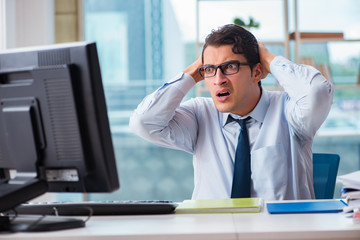 Unhappy businessman sitting at desk in office