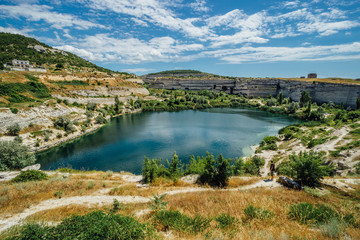 Fototapeta na wymiar Flooded quarry in Inkerman, Crimea. Blue pond on the place of former whiter limestone mine