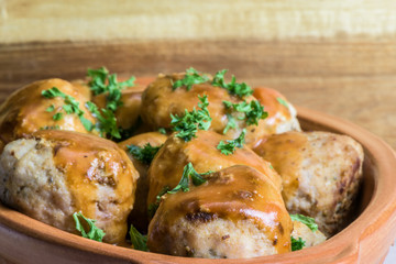 Fried meatballs in tomato sauce with parsley - wooden background - closeup