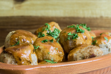 Baked meatballs in tomato sauce with parsley - wooden background - closeup