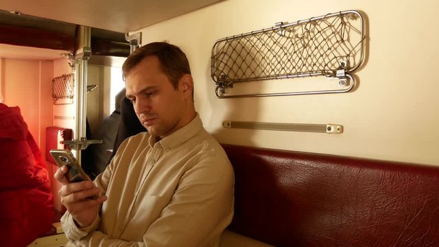 A person uses a smartphone in a compartment of a passenger train. 4k
