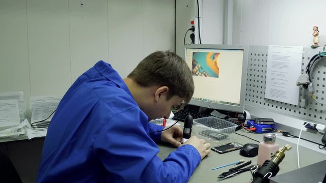 Service center. Electronics repair shops. The repair of the smartphone. Man repairing a smartphone. Electron microscope.