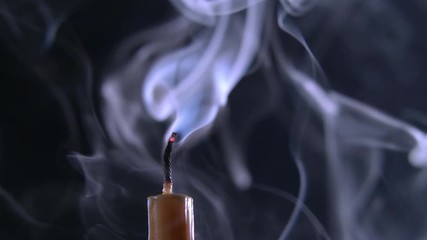 Candle is on and goes out. Black background. Close up