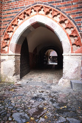 Fototapeta na wymiar Gate in Castle of the Teutonic Order in Malbork, Poland. Red brick wall and cobblestone.
