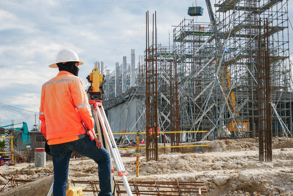 Wall mural surveyor builder engineer with theodolite transit equipment at construction site outdoors during sur