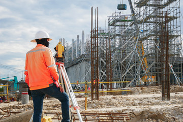 Surveyor builder Engineer with theodolite transit equipment at construction site outdoors during...