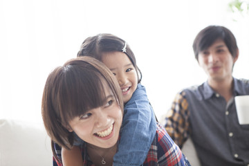 Parents and daughter are sitting on the sofa and talking.