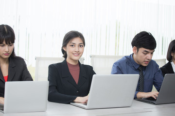 Obraz premium Asian Woman sitting in front of her team with smiling, Female with her team working in the office, Woman Leader Concept.