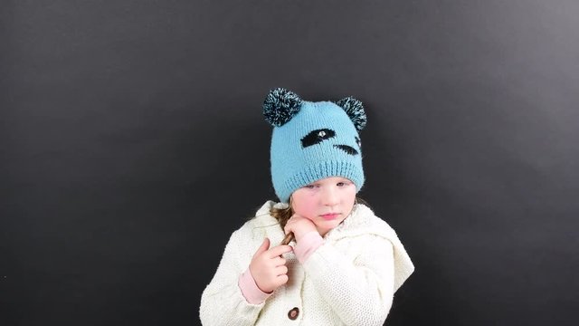 Small girl is dressed in winter clothing. Cute little girl on black background.