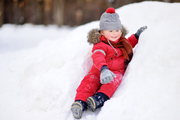 Fototapeta na wymiar Little boy in red winter clothes having fun with fresh snow