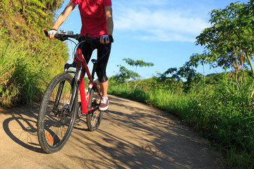 Fototapeta na wymiar female cyclist riding mountain bike on country road