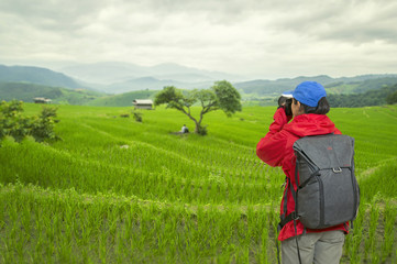Young girl with backpack taking photo of amazing landscape sunset.Beautiful rice terraces at Chaing Mai,Thailand.