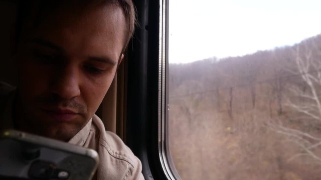 A person uses a smartphone in a compartment of a passenger train. 4k