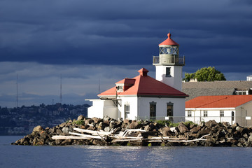 Fototapeta na wymiar High contrast image of Seattle's Alki Point Lighthouse taken from the water on a cloudy, sunlit day