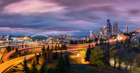 Foto op Aluminium Seattle cityscape at dusk with skyscrapers, winding highways parks and sports arenas under a dramatic sky. © mandritoiu