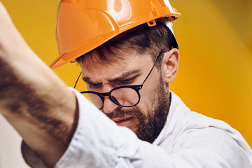 Engineer with a beard in glasses and a helmet on a yellow background, emotions