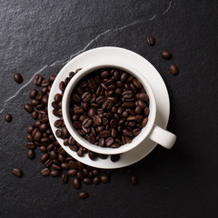 Coffee beans in the cup on the black stone.