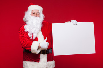 Santa Claus pointing in blank advertisement banner isolated on red background with copy space