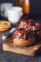Chocolate mini bundt cakes with chocolate glaze on wooden board. Closeup view, vertical composition