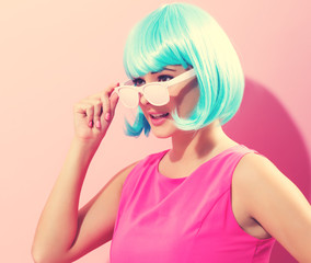 Portrait of a woman in a bright blue wig on a pink background
