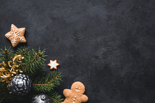 Christmas background. Gingerbread cookies, fir tree, christmas toys and holiday decorations frame on blackboard or stone backdrop. Top view with copy space for text