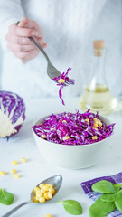 Salad of red cabbage and corn. Woman's hand holds fork with salad