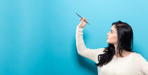 Obraz premium Young woman holding a pen on a solid background