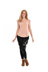 full length portrait of a girl wearing pink shirt and black floral pants. standing pose, isolated on white background.