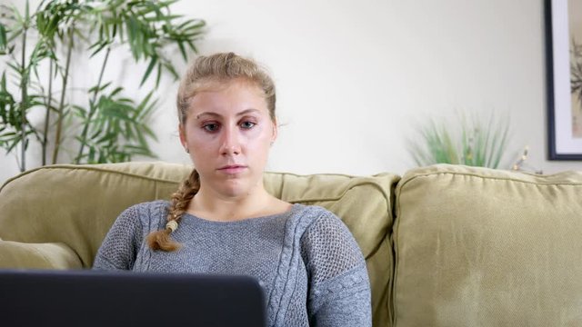 Young Woman typing on her laptop in modern living room ALT