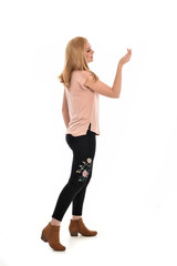 full length portrait of a girl wearing pink shirt and black floral pants. standing pose, isolated on white background.