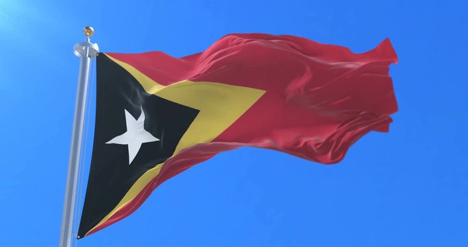 East Timorese flag waving at wind with blue sky in slow, loop