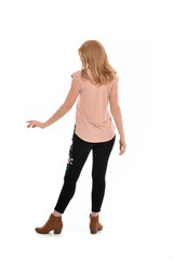 full length portrait of a girl wearing pink shirt and black floral pants. standing pose, isolated on white background.