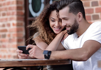 Happy loving  couple using a smartphone sitting in terrace