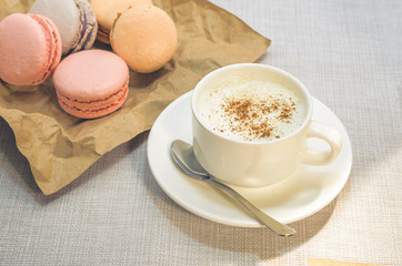 Cake macaroon on the plate,cinnamon and a frothy coffee close up
