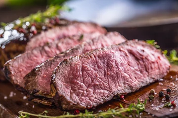 Foto op Aluminium Beef steak. Juicy medium Rib Eye steak slices on wooden board with fork and knife herbs spices and salt © weyo