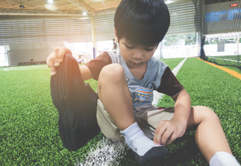 Boy taking shoes off getting ready for soccer training ground