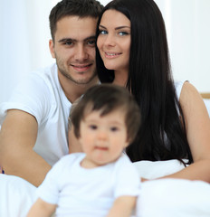 Fototapeta premium Cute little boy with parents on the bed