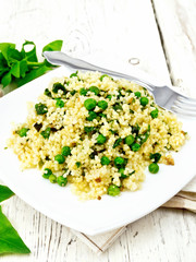 Couscous with spinach in plate on board