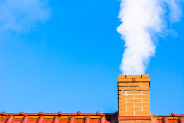 Modern house roof with chimney smoke, air pollution and smog in winter, ecological problems - obrazy, fototapety, plakaty