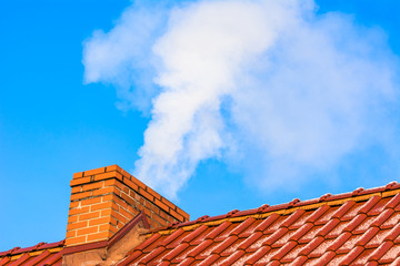Modern house roof with chimney smoke, air pollution and smog in winter, ecological problems