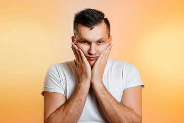 Portrait of a man close-up, who is surprised to spread his hands. On a light background. The concept of human emotions.