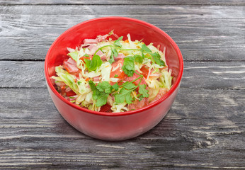 Vegetable salad with ham in the red salad bowl