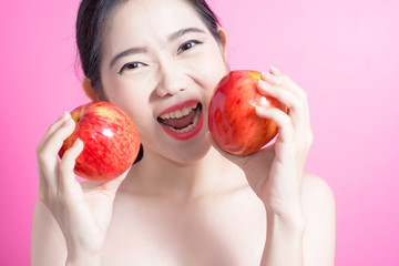 Asian woman with apple concept. She smiling and holding apple. Beauty face and natural makeup. Isolated over pink background.